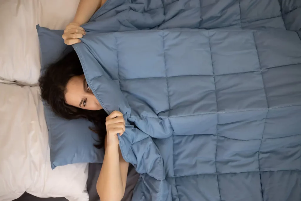 couverture lestée essentielle couleur bleu avec une femme allongée sur le lit