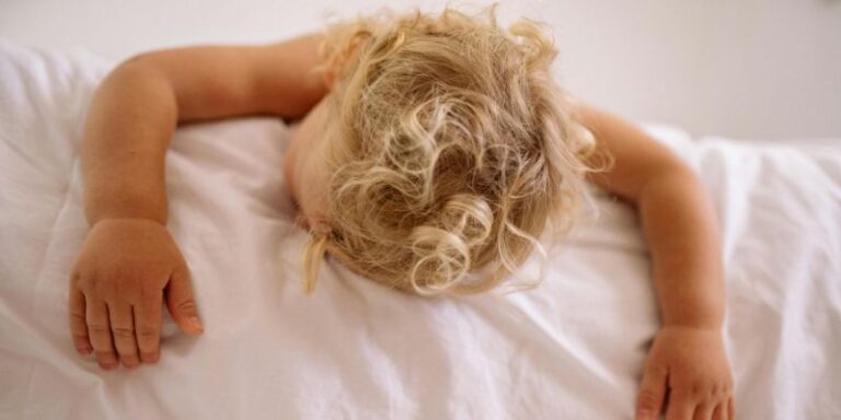 un enfant blond qui dort sur son lit en été