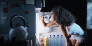 femme qui boit de l'eau glacé car elle a chaud la nuit