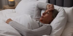 femme qui a chaud et se tient la tête dans son lit