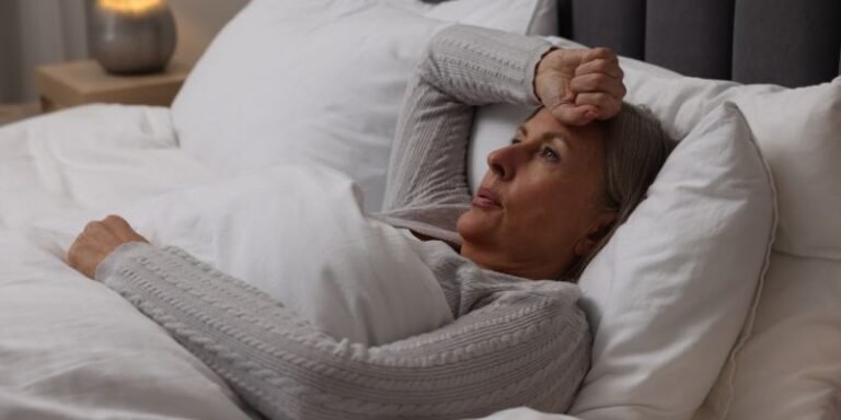 femme qui a chaud et se tient la tête dans son lit