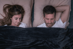 2 personnes couchées sous une couverture lestée