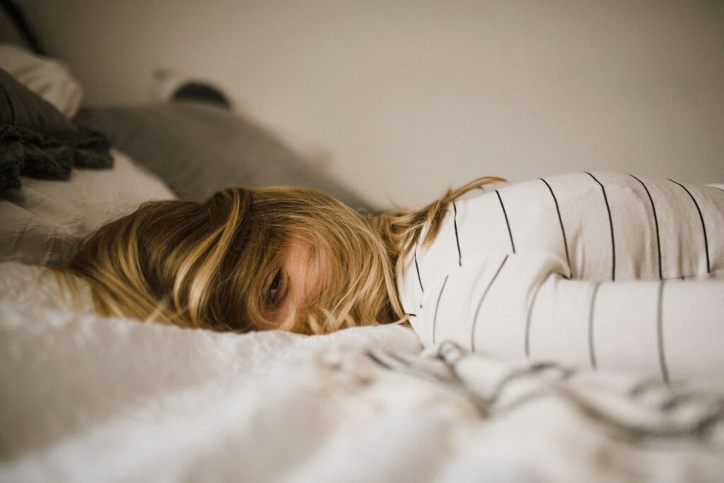 femme blonde avec regard souriant allongé sur un lit