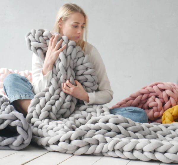 une femme blonde avec une couverture lestée tricotée en coton