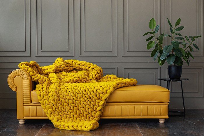 couverture lestée tricotée laine couleur moutarde sur canapé jaune