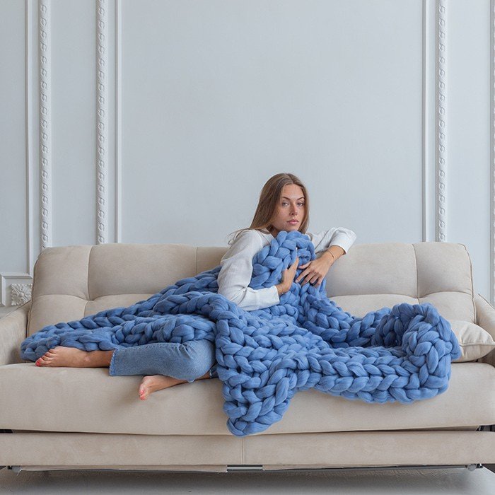 femme couverture lestée tricotée laine couleur lavande sur un canapé